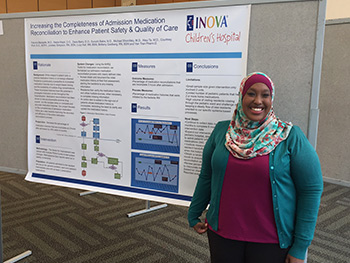 One resident in front of a research poster at a conference