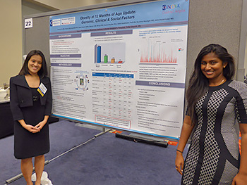 Two residents pose in front of a research poster at a conference