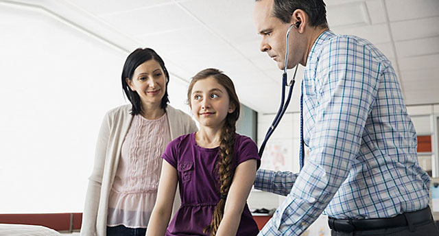 Doctor examining girl with mother from side 