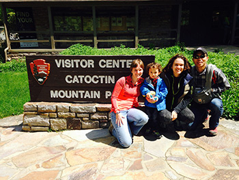 three residents with a toddler pose by the Catoctin Mountain Park sign