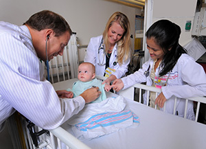 three doctors observing a baby