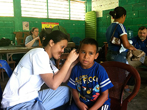 a resident in a community clinic looking in a little boy's ear