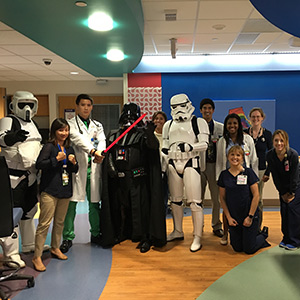 doctors and nurses pose with characters dressed in Star Wars visiting the hospital