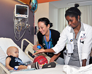 Two Inova pediatric residents caring for a hospitalized toddler in bed